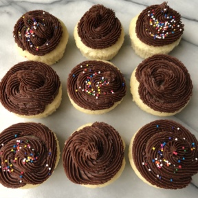 Nine Yellow Cupcakes with Chocolate Frosting