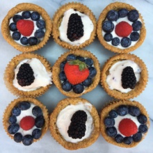Gluten-free chocolate chip cookie cups filled with ice cream and berries