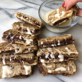 Cinnamon Roll French Toast Sticks dipping into icing