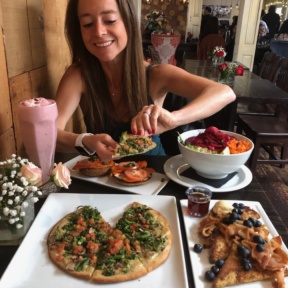 Jackie eating gluten-free vegan pizza from Suncafe