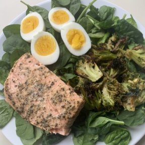 Baked salmon on spinach salad with broccoli and eggs
