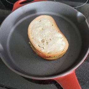 Cooking gluten-free Mozzarella Pesto Tomato Panini in cast iron skillet